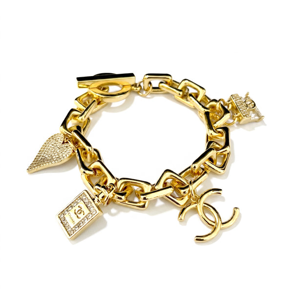 Gold chain charm bracelet with pave heart, perfume bottle and crystal charms and a toggle clasp